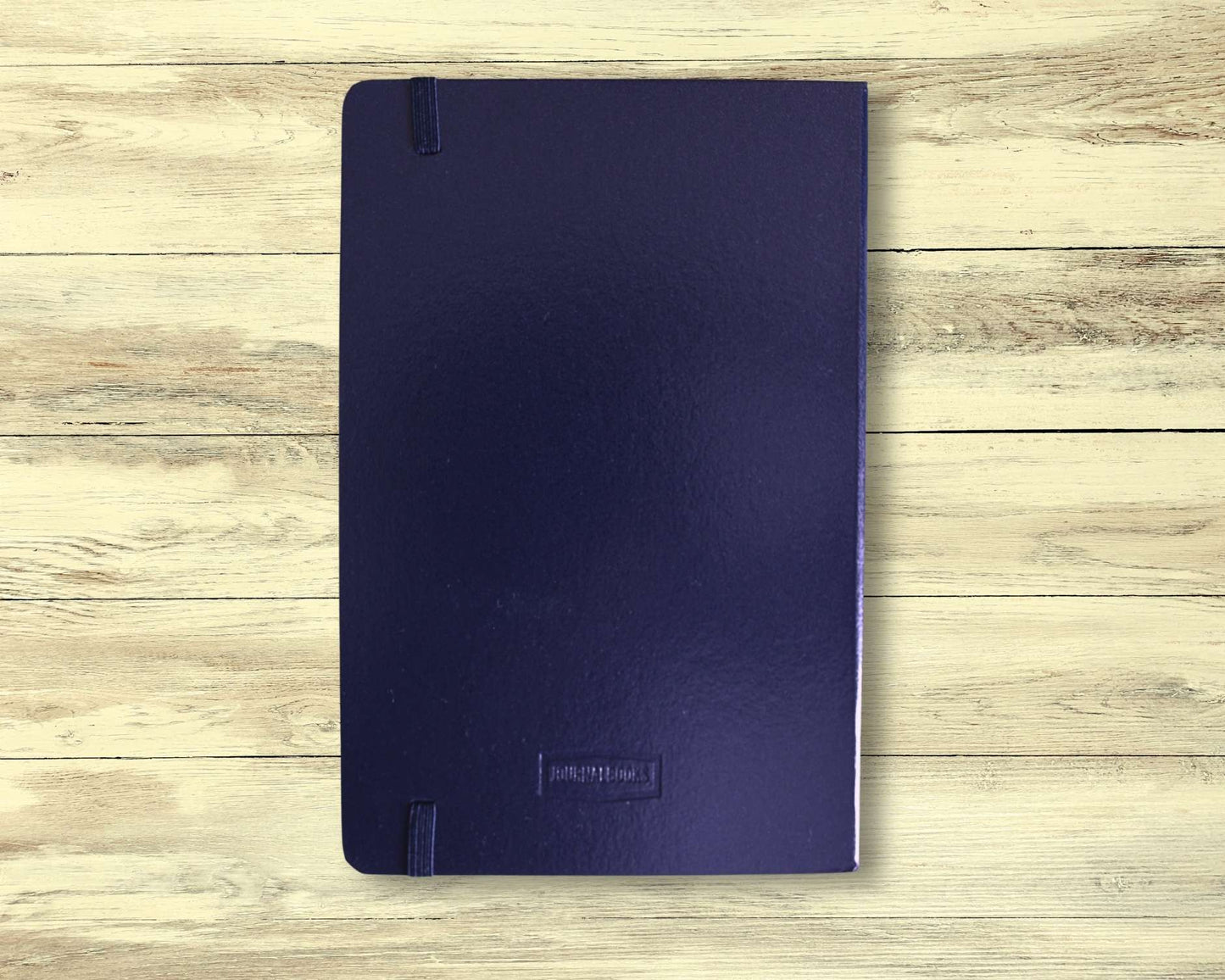 Back cover of dark blue meditation journal displayed on light wooden floorboards — plain design, used for mindfulness, reflection, and intention setting.