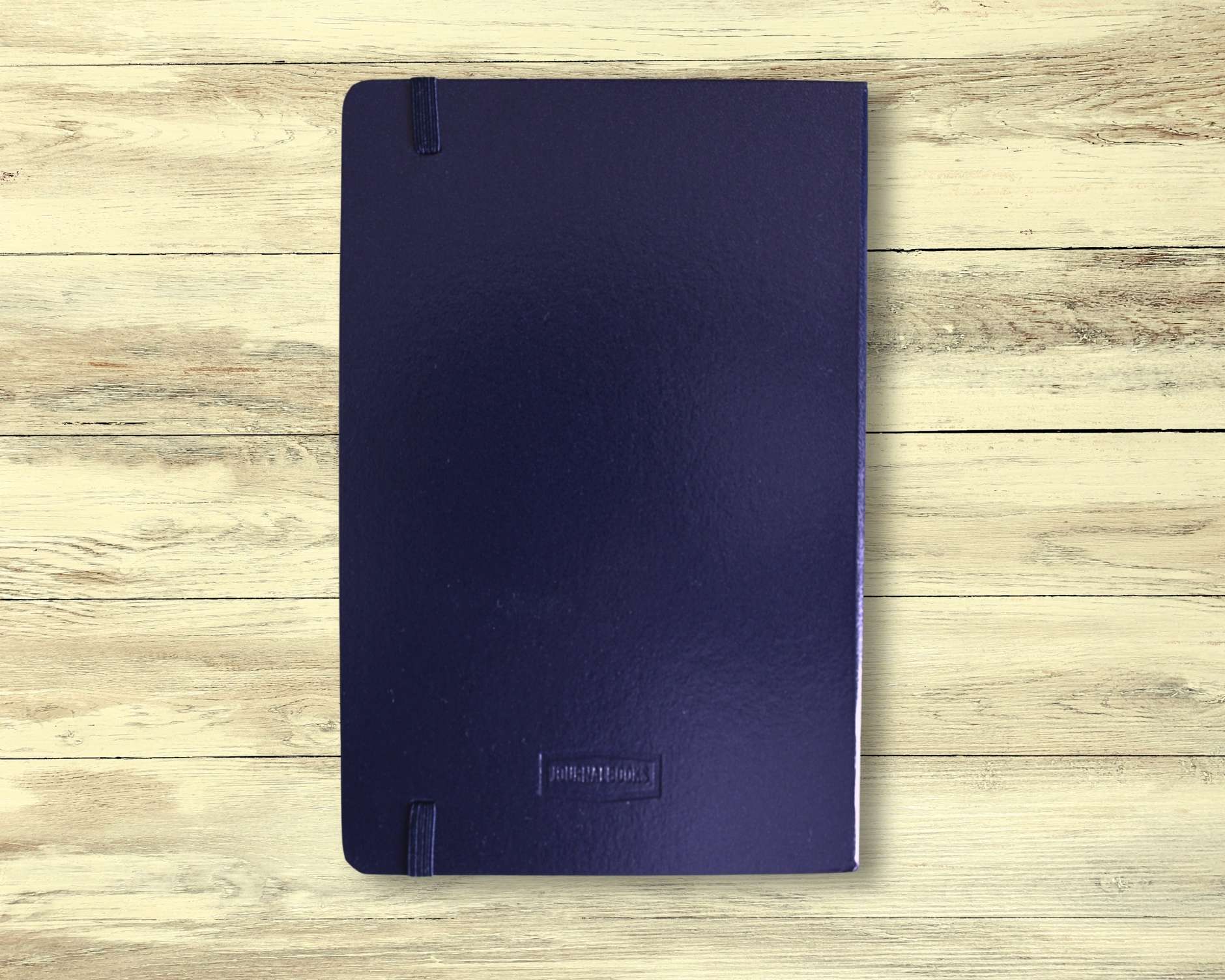 Back cover of dark blue meditation journal displayed on light wooden floorboards — plain design, used for mindfulness, reflection, and intention setting.