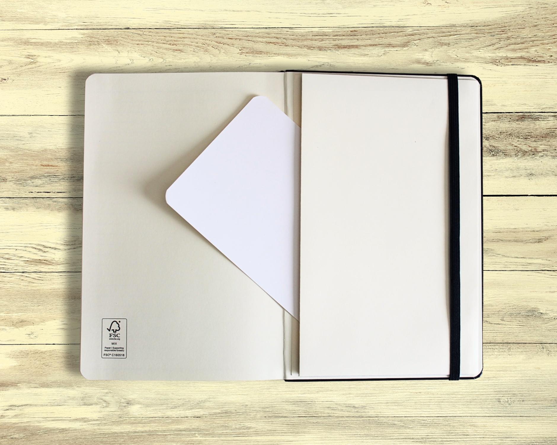 Open meditation journal showing the expandable accordion pocket on the last page with a blank A6 card half inserted — displayed on light wooden floorboards, designed for mindfulness and journaling reflections.